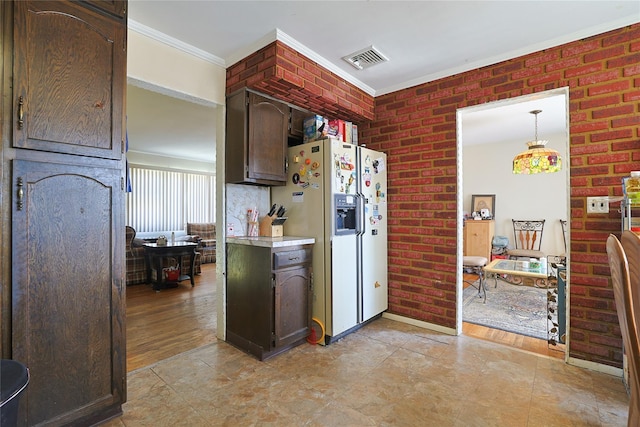 kitchen with ornamental molding, white refrigerator with ice dispenser, light countertops, dark brown cabinets, and visible vents