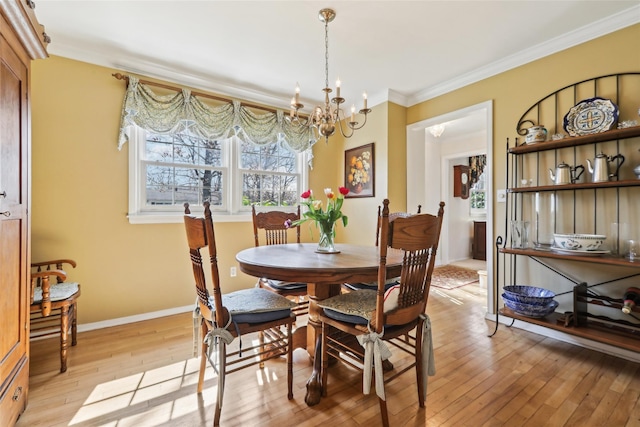 dining area with a chandelier, a healthy amount of sunlight, light wood-style floors, and crown molding