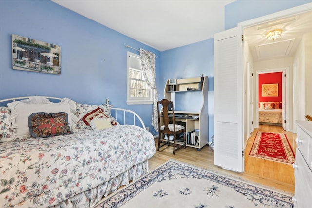bedroom featuring attic access and wood finished floors