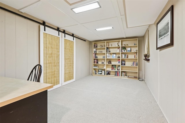 unfurnished office with a barn door and carpet flooring
