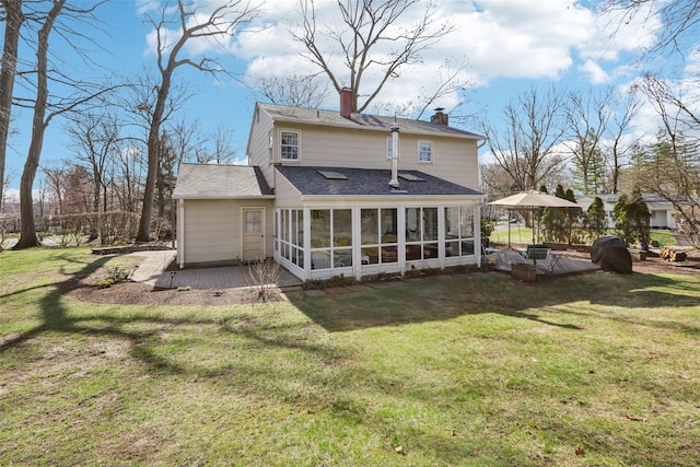 back of house featuring a lawn, a chimney, a patio area, and a sunroom