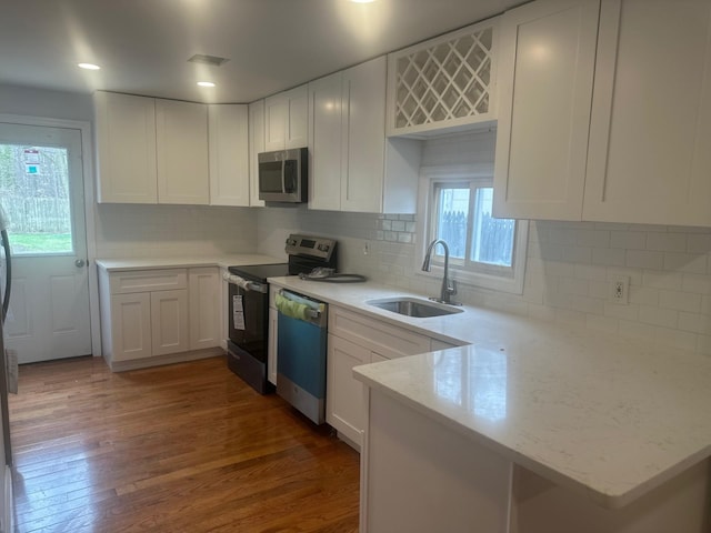 300 Prairie Dr, North Babylon, NY 11703 - kitchen featuring dark wood-style flooring, appliances with stainless steel finishes, a sink, white cabinets, and a peninsula
