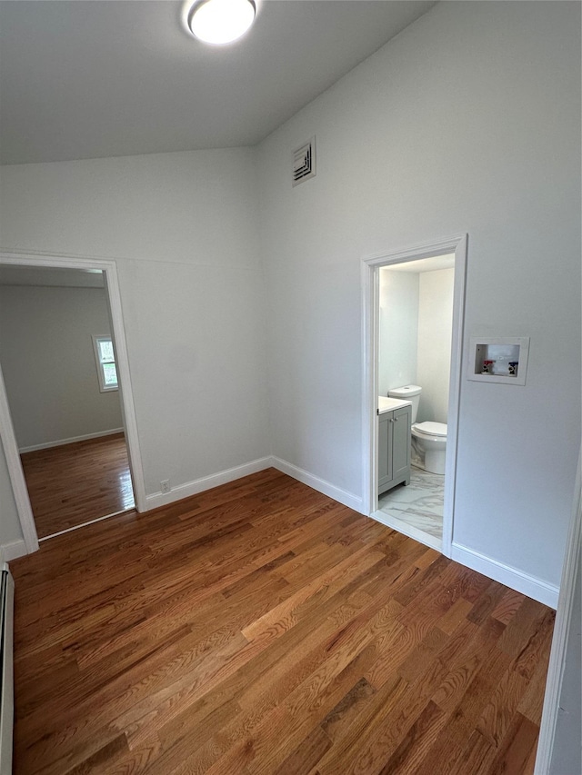 300 Prairie Dr, North Babylon, NY 11703 - unfurnished bedroom featuring visible vents, ensuite bathroom, baseboards, high vaulted ceiling, and light wood-style flooring