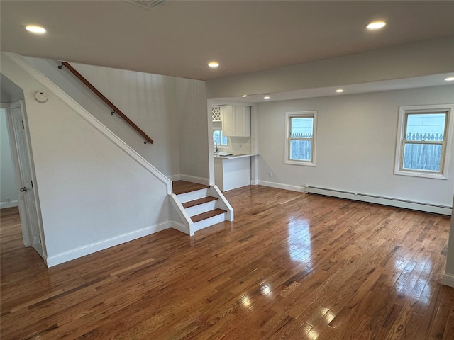 300 Prairie Dr, North Babylon, NY 11703 - unfurnished living room with a sink, stairs, recessed lighting, wood finished floors, and a baseboard radiator