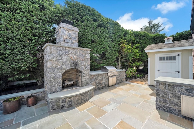 view of patio / terrace featuring an outdoor stone fireplace, exterior kitchen, grilling area, and fence