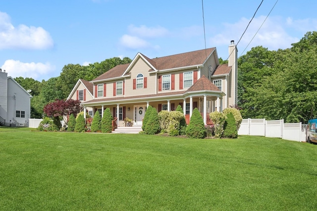 colonial-style house with a front yard, fence, covered porch, and a chimney