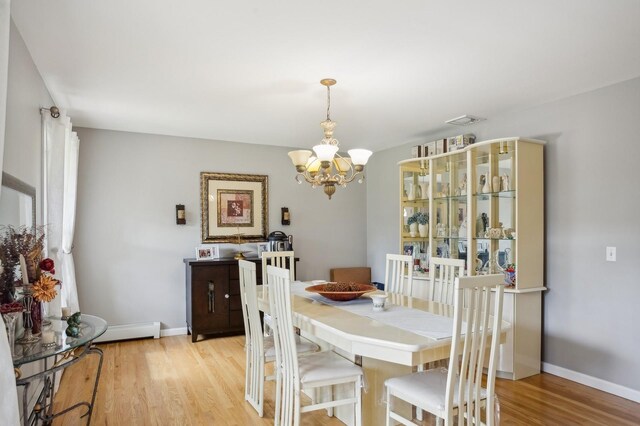 dining space featuring visible vents, a baseboard heating unit, baseboards, an inviting chandelier, and light wood-type flooring