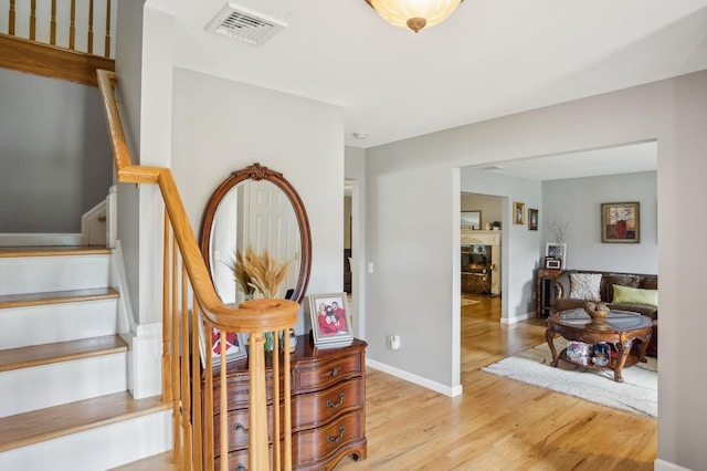 staircase with a tile fireplace, visible vents, wood finished floors, and baseboards