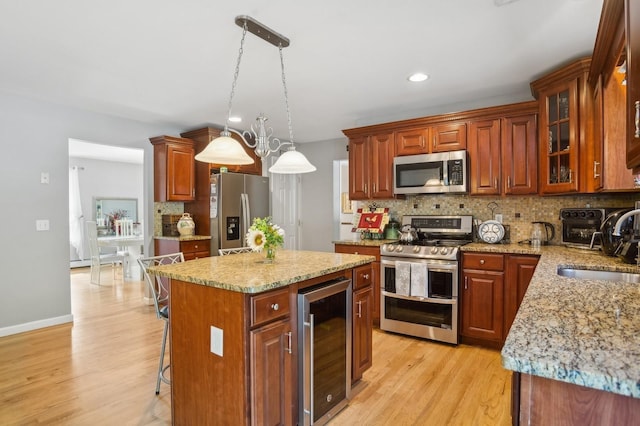 kitchen with a sink, wine cooler, tasteful backsplash, light stone counters, and appliances with stainless steel finishes