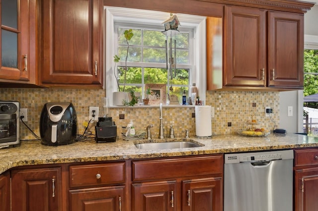 kitchen featuring a sink, glass insert cabinets, light stone counters, backsplash, and stainless steel dishwasher