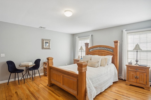 bedroom featuring visible vents, light wood-style flooring, baseboard heating, and baseboards