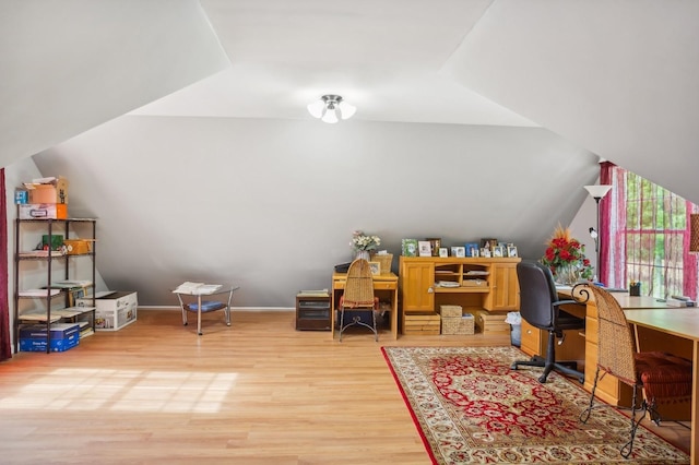 home office featuring baseboards, lofted ceiling, and light wood-type flooring