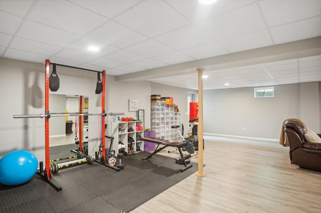 workout area featuring baseboards, wood finished floors, and a paneled ceiling