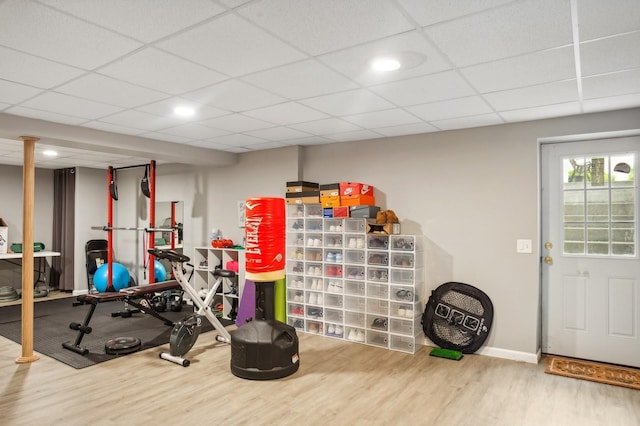 exercise room featuring baseboards, wood finished floors, and a paneled ceiling