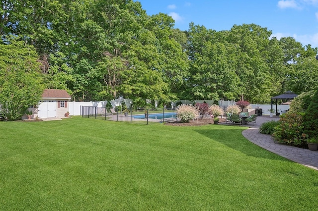 view of yard with a patio area, a fenced in pool, a storage unit, a fenced backyard, and a gazebo