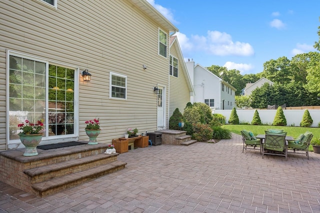 rear view of house featuring outdoor dining area, a yard, a patio area, and fence