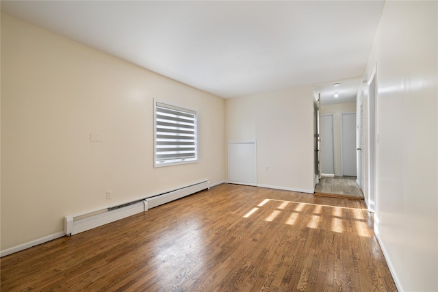 unfurnished room featuring baseboards, a baseboard radiator, and wood finished floors