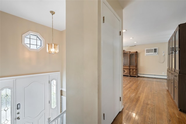 foyer with an inviting chandelier, a baseboard radiator, light wood-style floors, and a wealth of natural light