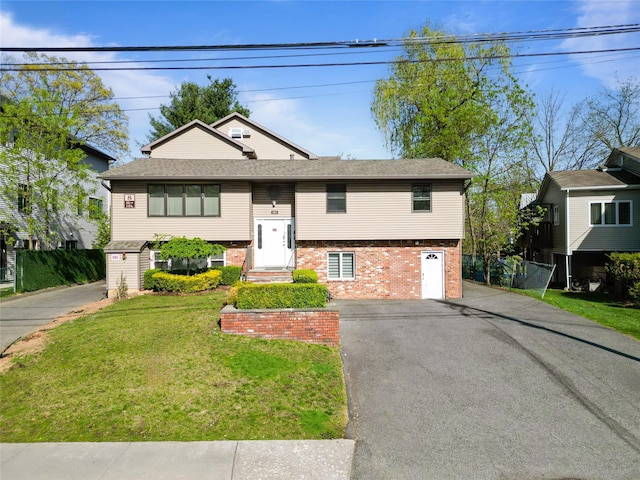 bi-level home featuring brick siding, a front lawn, and aphalt driveway
