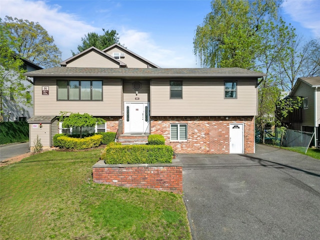 split foyer home featuring fence, driveway, a front lawn, and brick siding