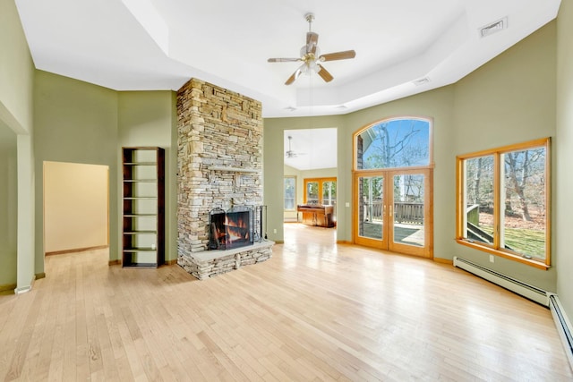 64 Turtle Cove Dr, Southampton, NY 11968 - unfurnished living room featuring visible vents, a ceiling fan, a stone fireplace, a tray ceiling, and wood-type flooring