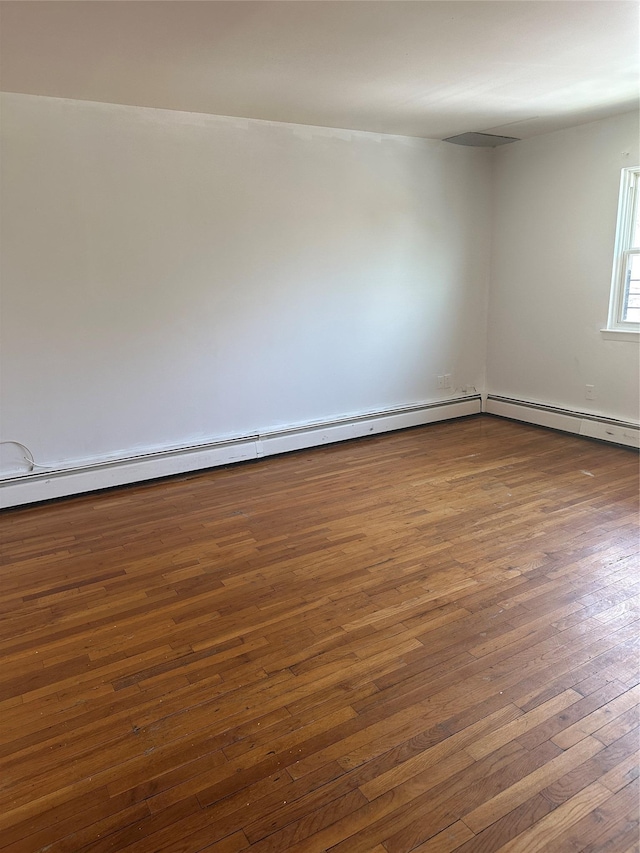 spare room featuring dark wood finished floors and baseboard heating