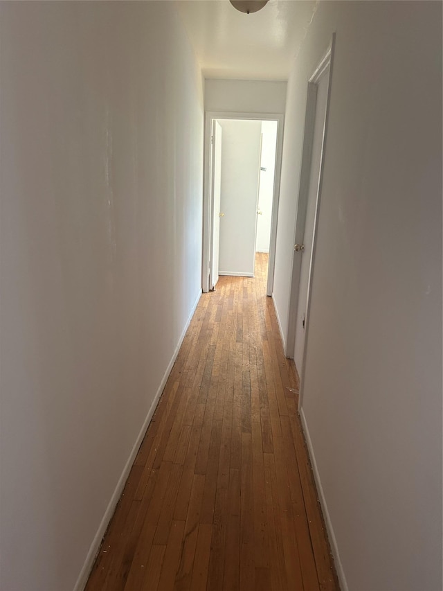 corridor with baseboards and dark wood-style flooring