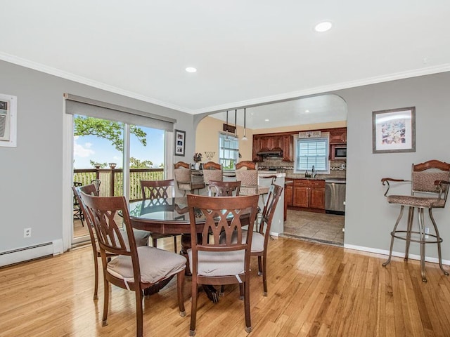 dining area featuring arched walkways, light wood finished floors, crown molding, a baseboard radiator, and recessed lighting