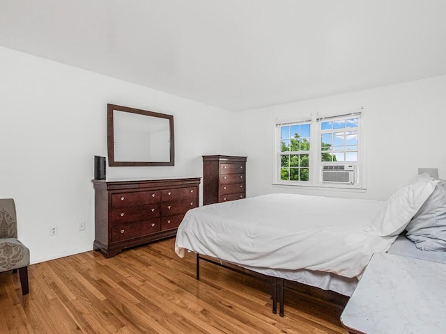 bedroom featuring wood finished floors, cooling unit, and baseboards