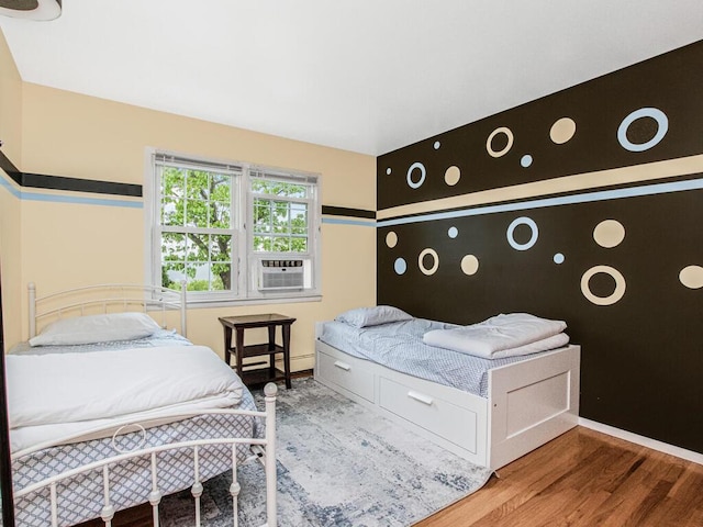 bedroom with wood finished floors, baseboards, and cooling unit