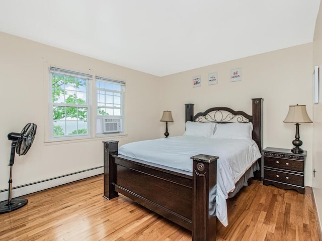 bedroom with wood finished floors, a baseboard heating unit, and cooling unit