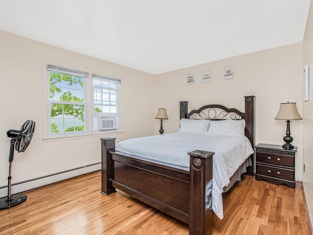 bedroom featuring light wood-type flooring, a baseboard radiator, and cooling unit