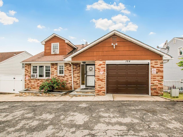 view of front of home featuring brick siding, fence, an attached garage, and asphalt driveway