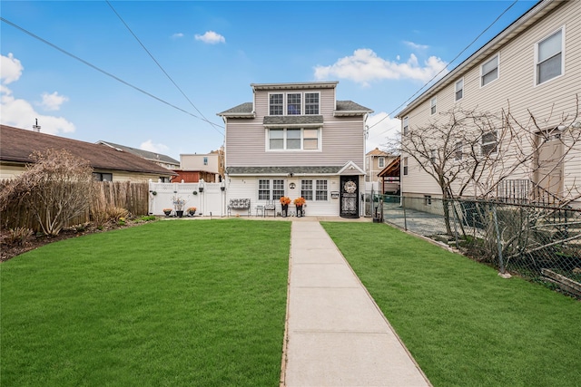 back of house with a fenced backyard, a lawn, a patio area, a gate, and a shingled roof