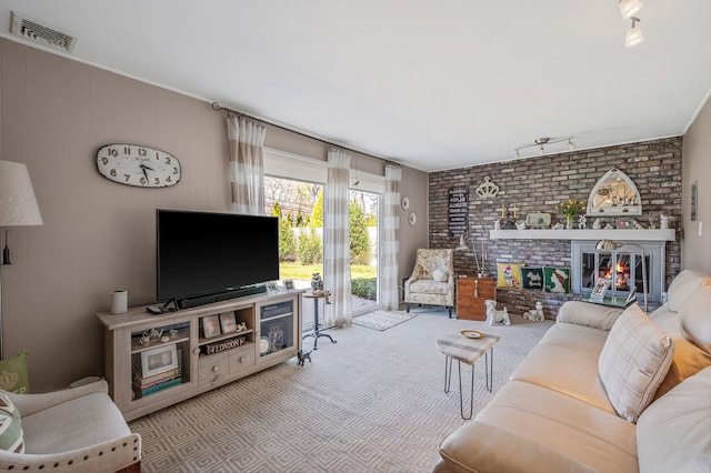 carpeted living room featuring rail lighting, a brick fireplace, and visible vents