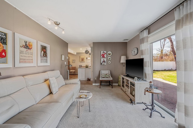 living area featuring baseboards, visible vents, and light colored carpet