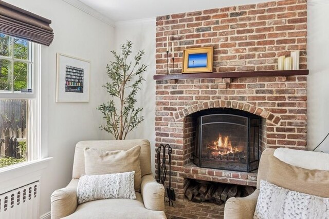 3320 Oregon Rd, Mattituck, NY 11952 - living area with radiator heating unit, a brick fireplace, and crown molding