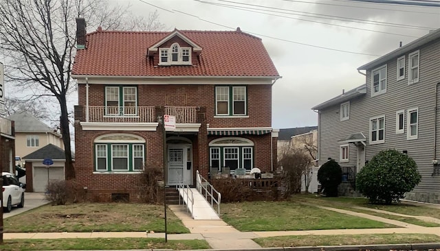 view of front of property featuring a chimney, brick siding, and a balcony