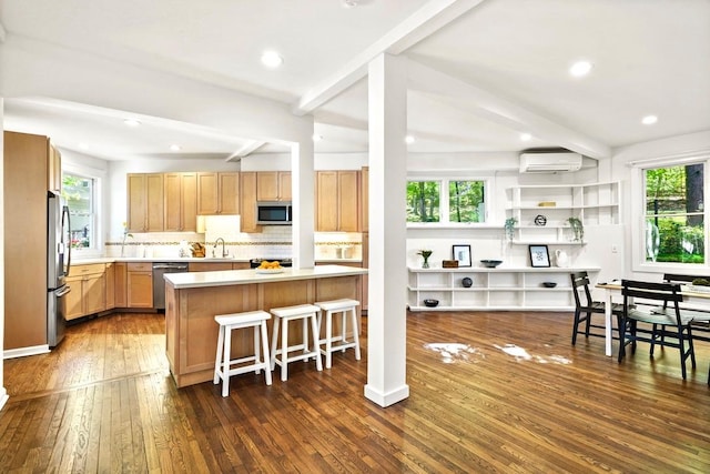 kitchen with a sink, beam ceiling, a breakfast bar, and stainless steel appliances