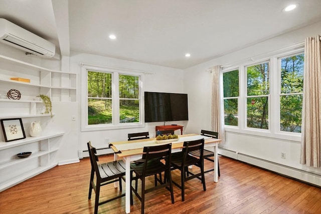 dining area with a healthy amount of sunlight, an AC wall unit, and hardwood / wood-style flooring
