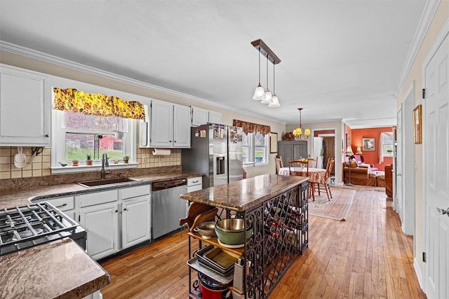 kitchen with stainless steel appliances, light wood-style floors, a sink, and ornamental molding