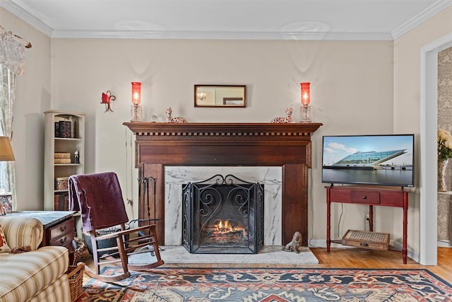 living room with a high end fireplace, wood finished floors, baseboards, and ornamental molding