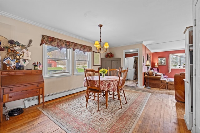 dining room with wood-type flooring, crown molding, a baseboard heating unit, and a notable chandelier