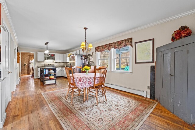 dining space with crown molding, a baseboard radiator, and light wood-type flooring