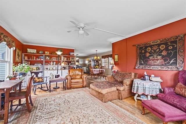 living area featuring ceiling fan with notable chandelier, wood finished floors, and ornamental molding
