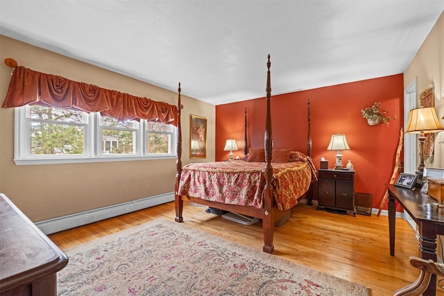 bedroom with a baseboard radiator, wood finished floors, and baseboards
