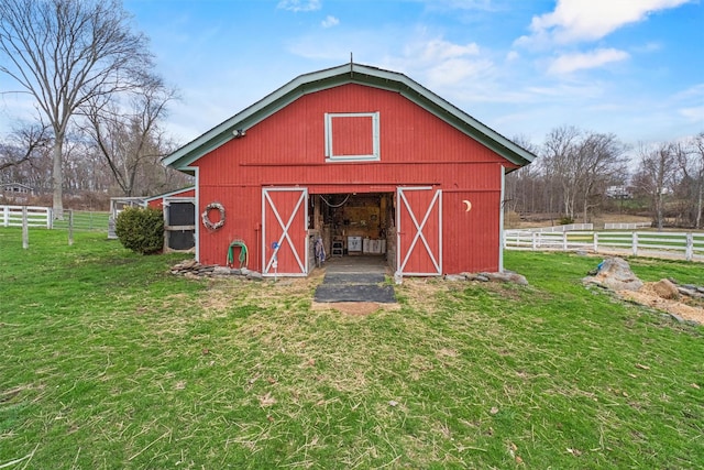 view of barn with fence and a lawn