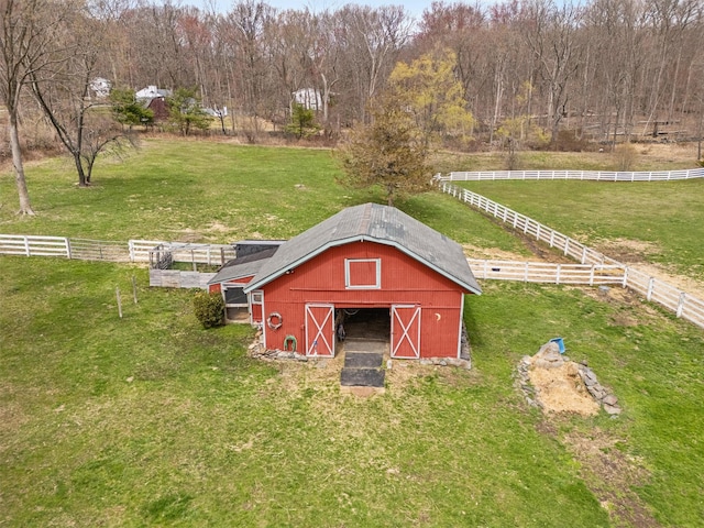 view of barn with a rural view, a yard, and fence