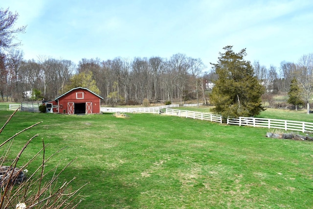 view of yard with a barn, an outdoor structure, fence, and a rural view