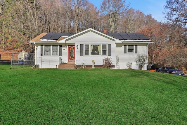 ranch-style home featuring solar panels, fence, and a front lawn